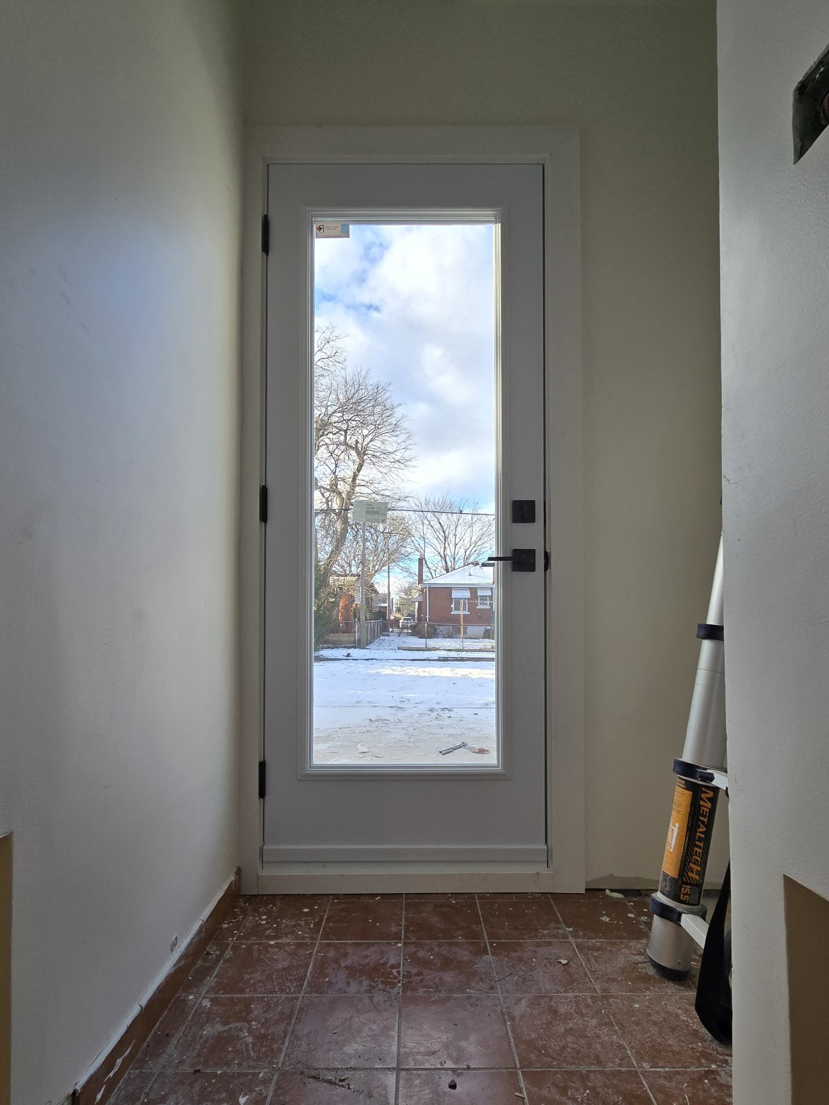 Interior view of a white full-glass exterior door at the end of a narrow hall