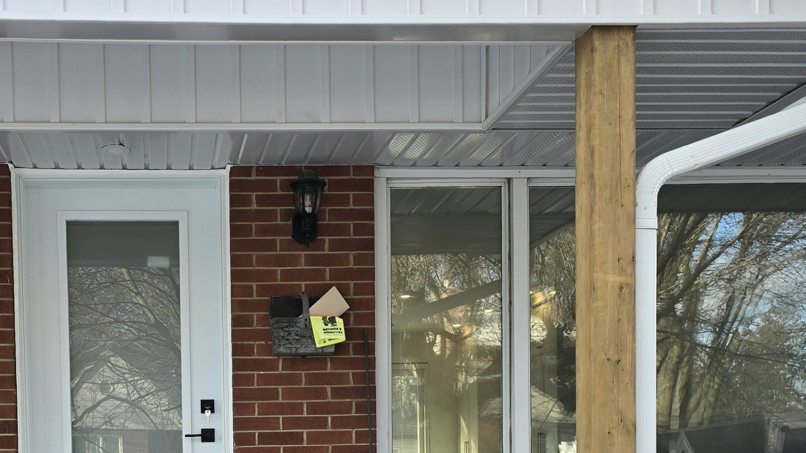 White full-glass exterior door beside a horizontal window during a porch renovation