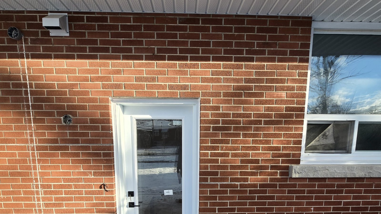 White full-glass exterior door installed in a red-brick Hamilton-area home
