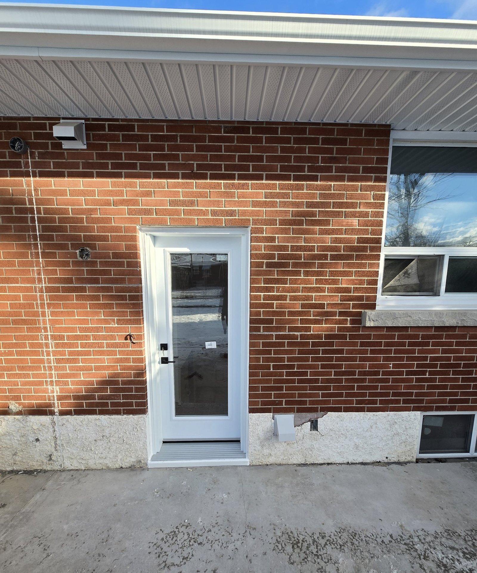 White full-glass rear exterior door installed in a Hamilton brick bungalow